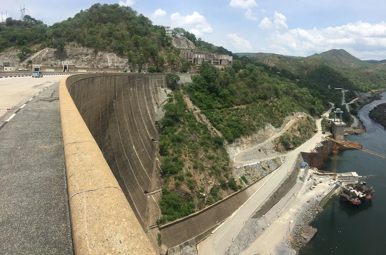 Curved concrete wall of the Kariba Dam seen from the crest, with the Zambezi gorge and hills below