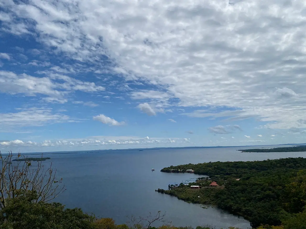 Wide view over Lake Itezhi-Tezhi and its wooded shoreline under a cloudy sky