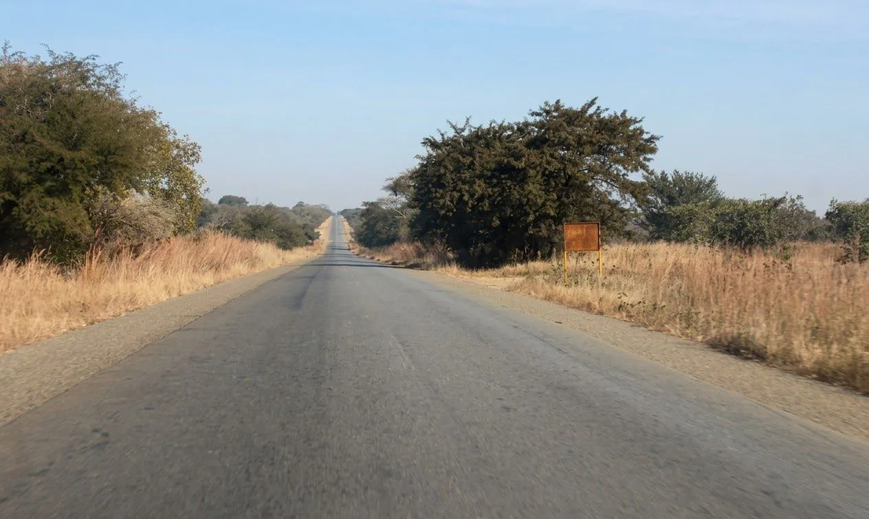 Straight open tar road running to the horizon through the Zambian bush